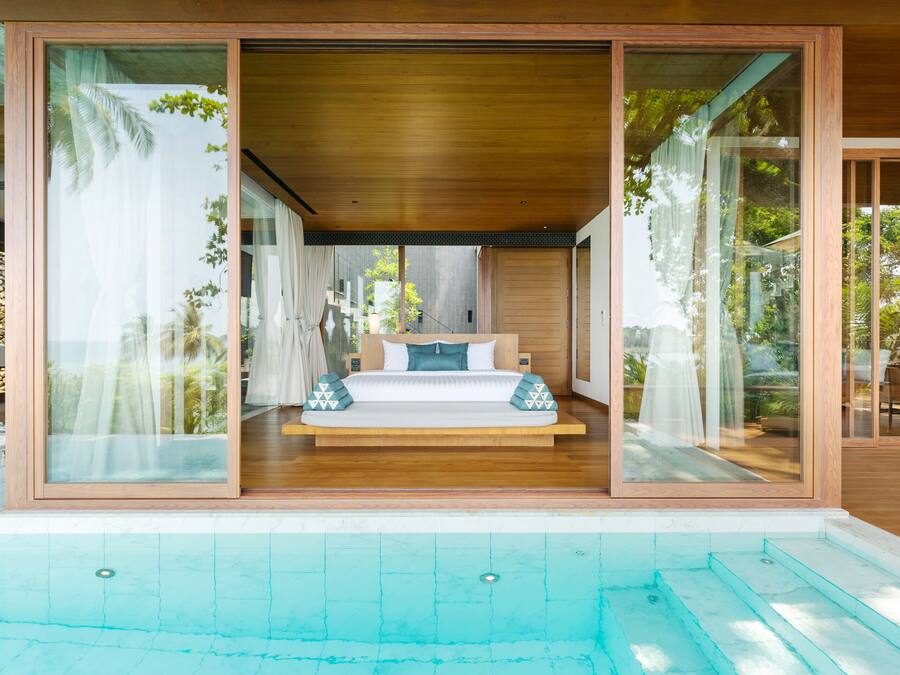 Un dormitorio moderno con una cama grande, vista a la piscina y una puerta corrediza de vidrio.