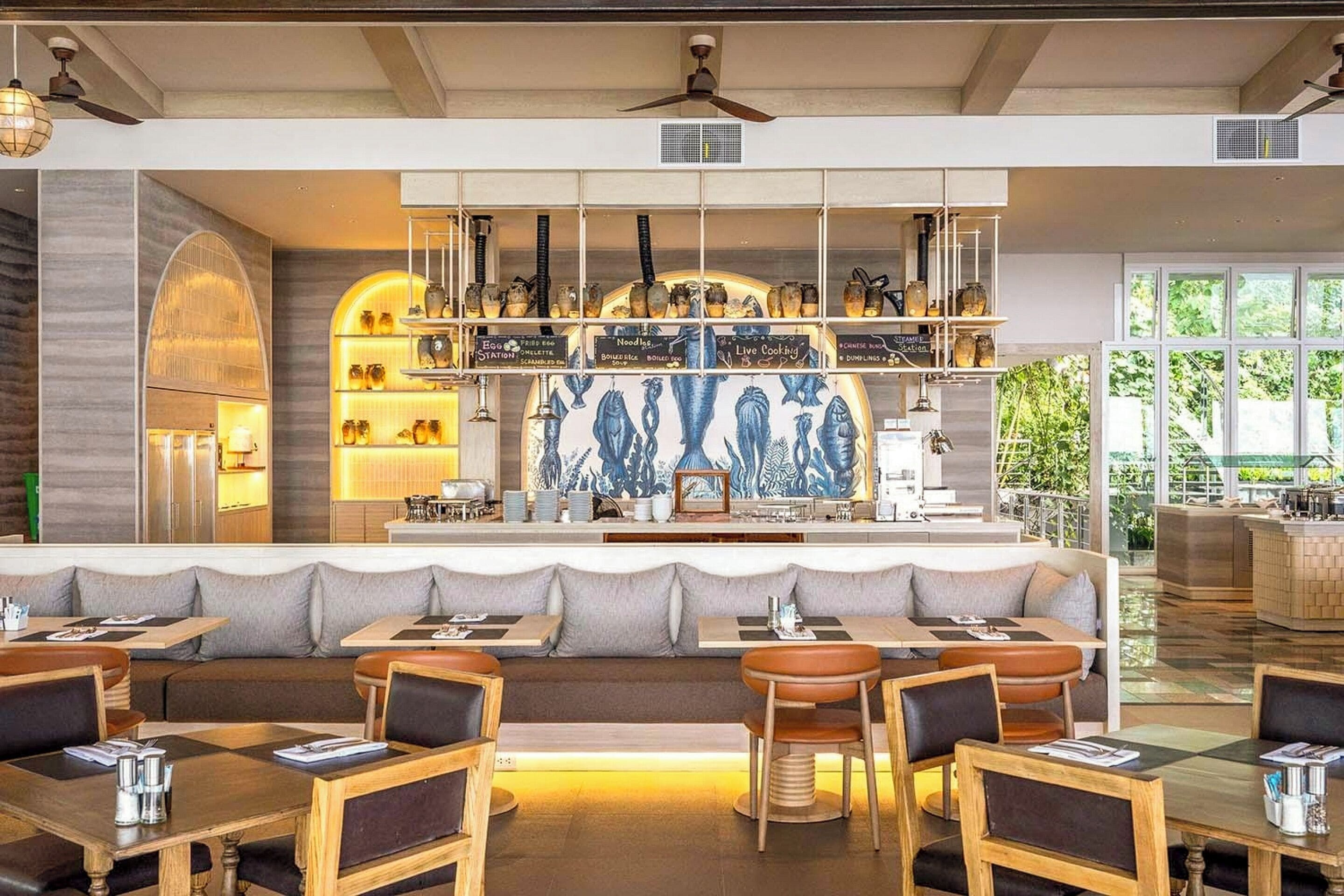 Un restaurante moderno con barra, diferentes disposiciones de asientos y una pared decorativa.
