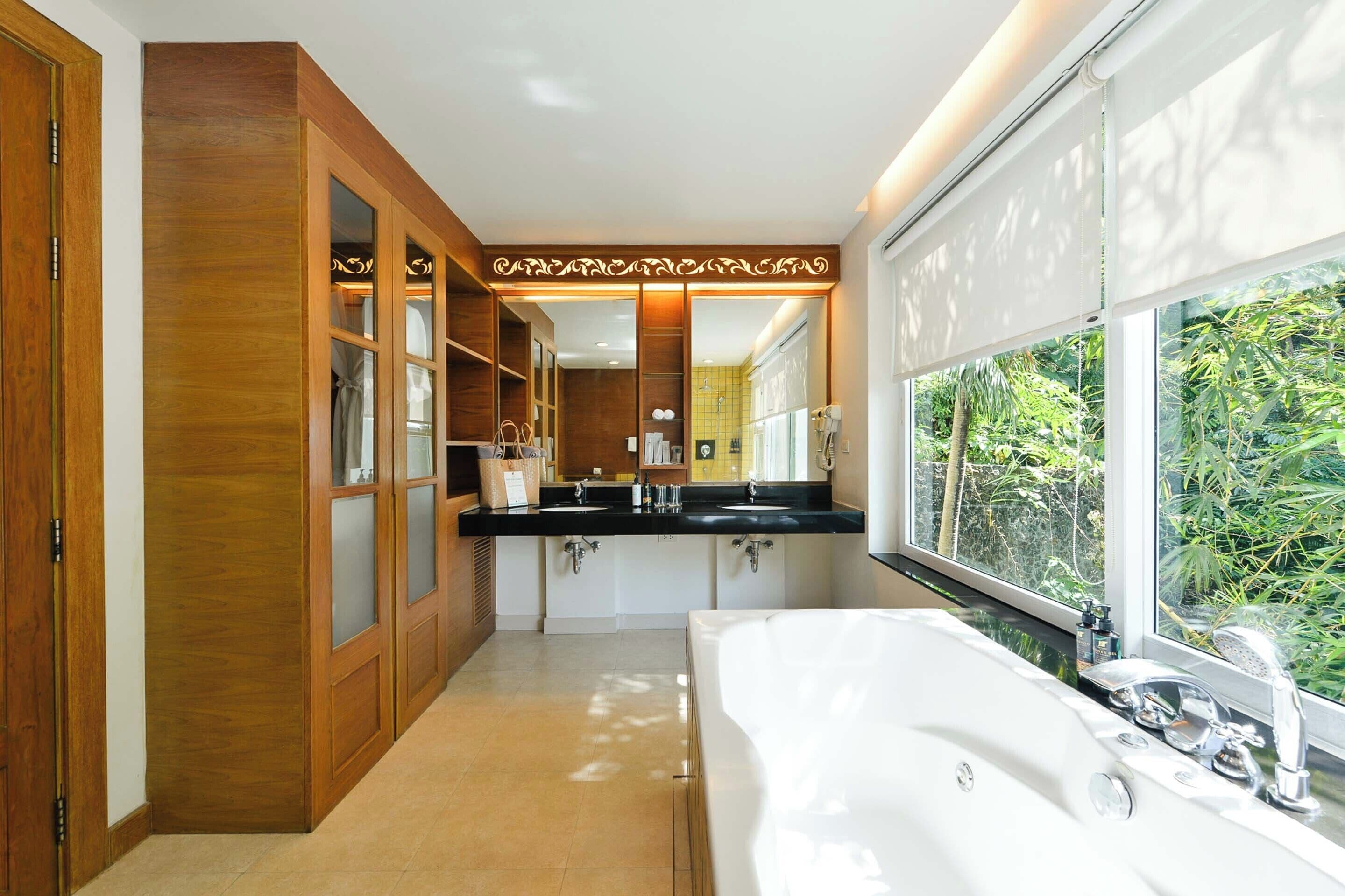A modern bathroom with a large bathtub, double sinks, and a large mirror.