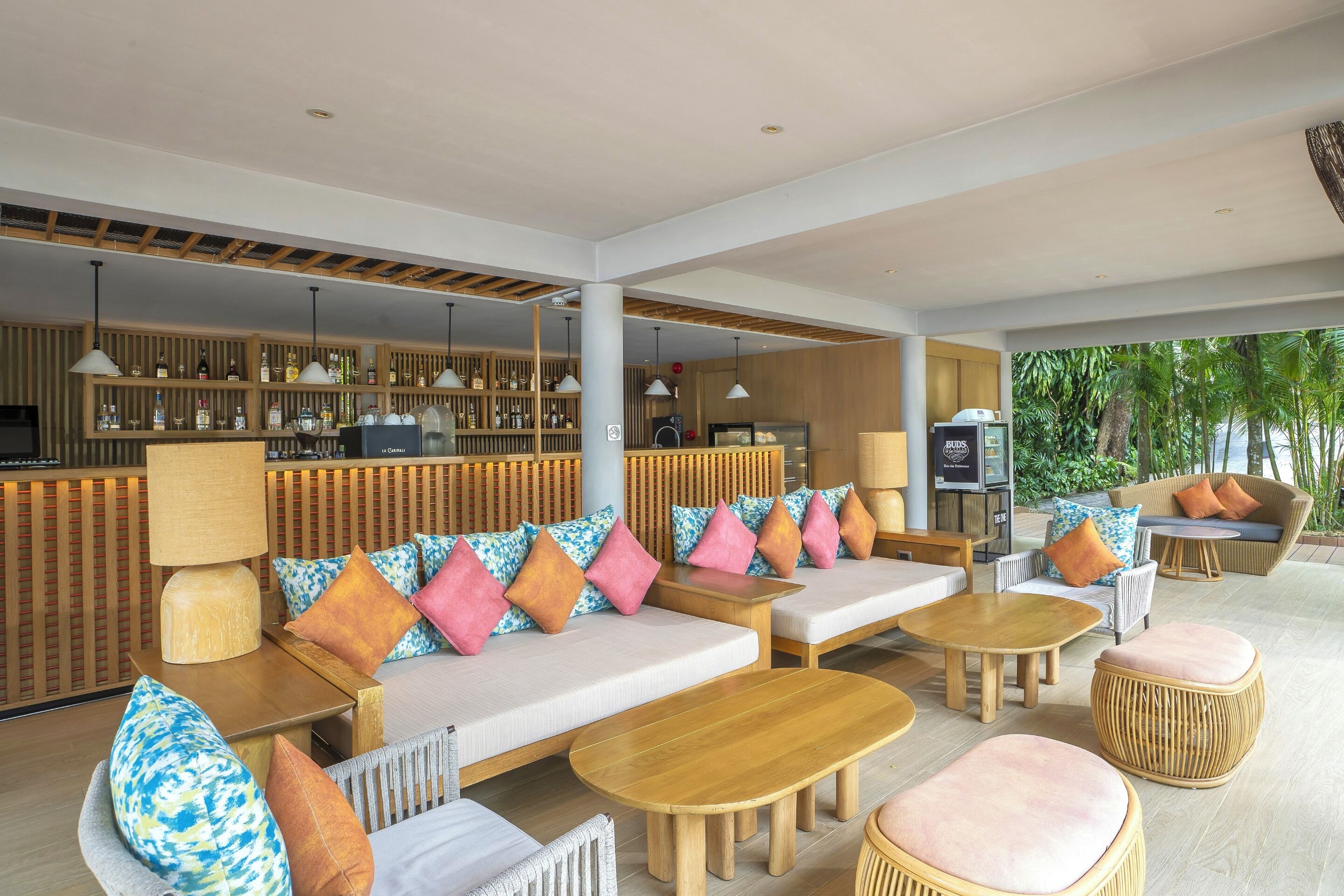 Een moderne lounge met een bar, zitgedeelte en uitzicht op groen.