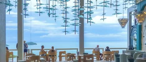A spacious outdoor seating area with tables and chairs, overlooking a body of water.