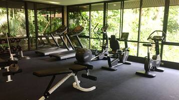 Un gimnasio con cintas de correr, máquinas de pesas y mancuernas.