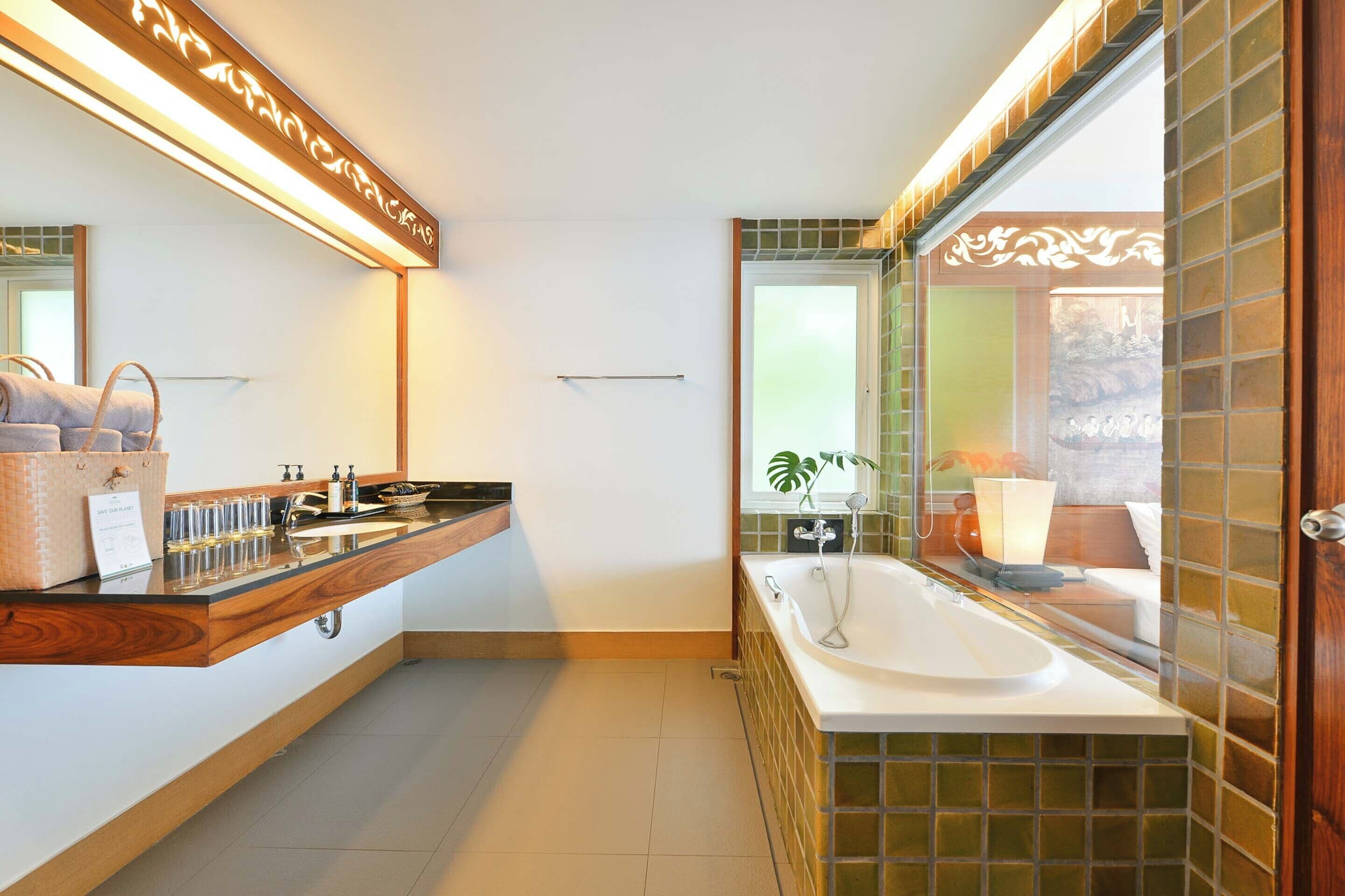 A modern bathroom with a wooden vanity, a freestanding bathtub, and a large mirror.