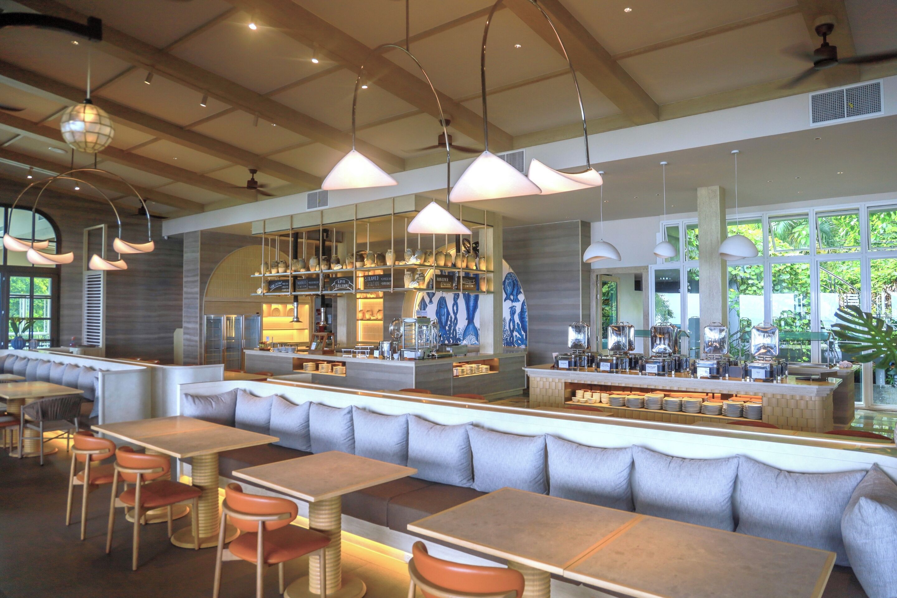 Un restaurant moderne avec de hauts plafonds, des luminaires suspendus et un bar central.
