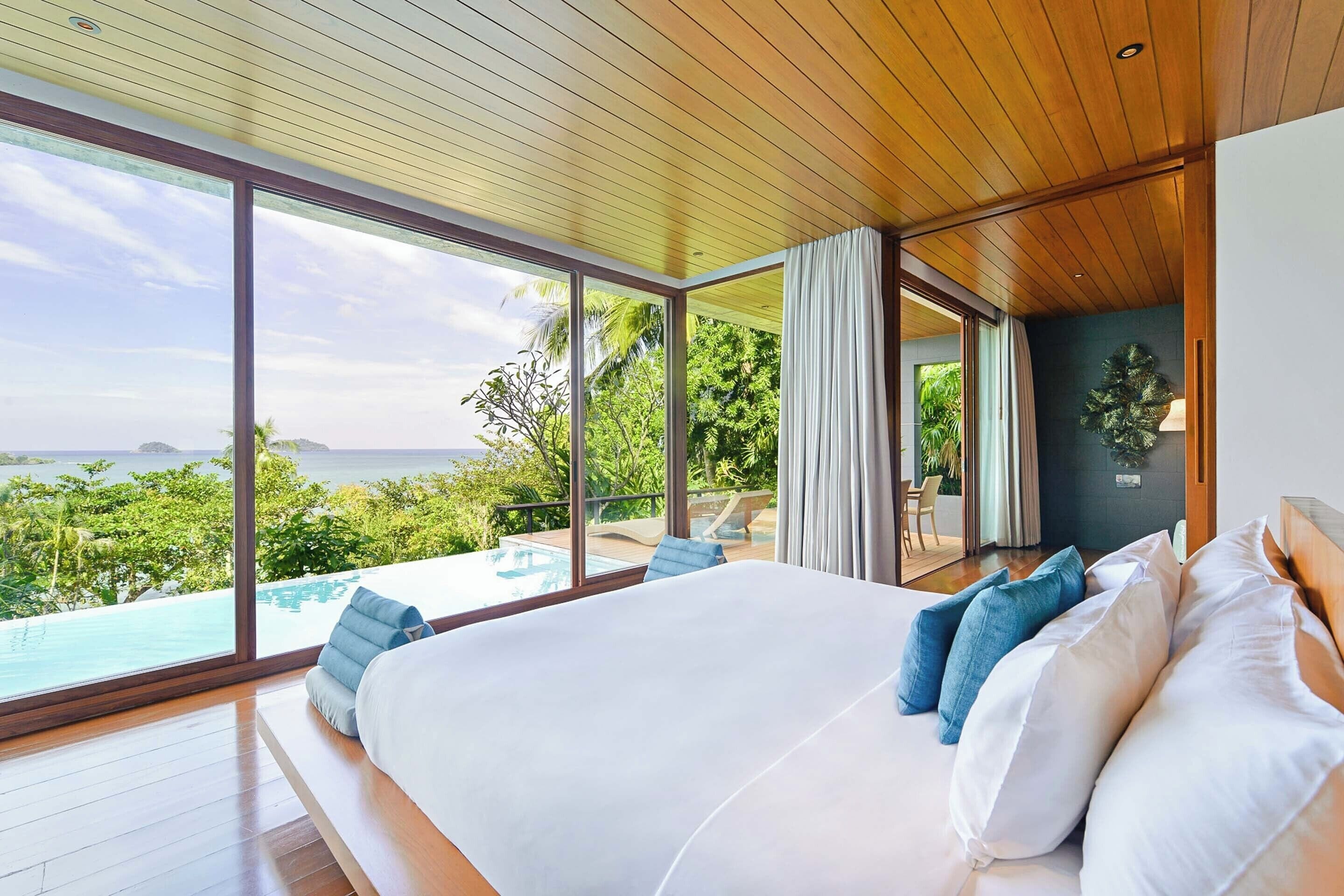 Un dormitorio con una cama grande, vista a una piscina y techo de madera.