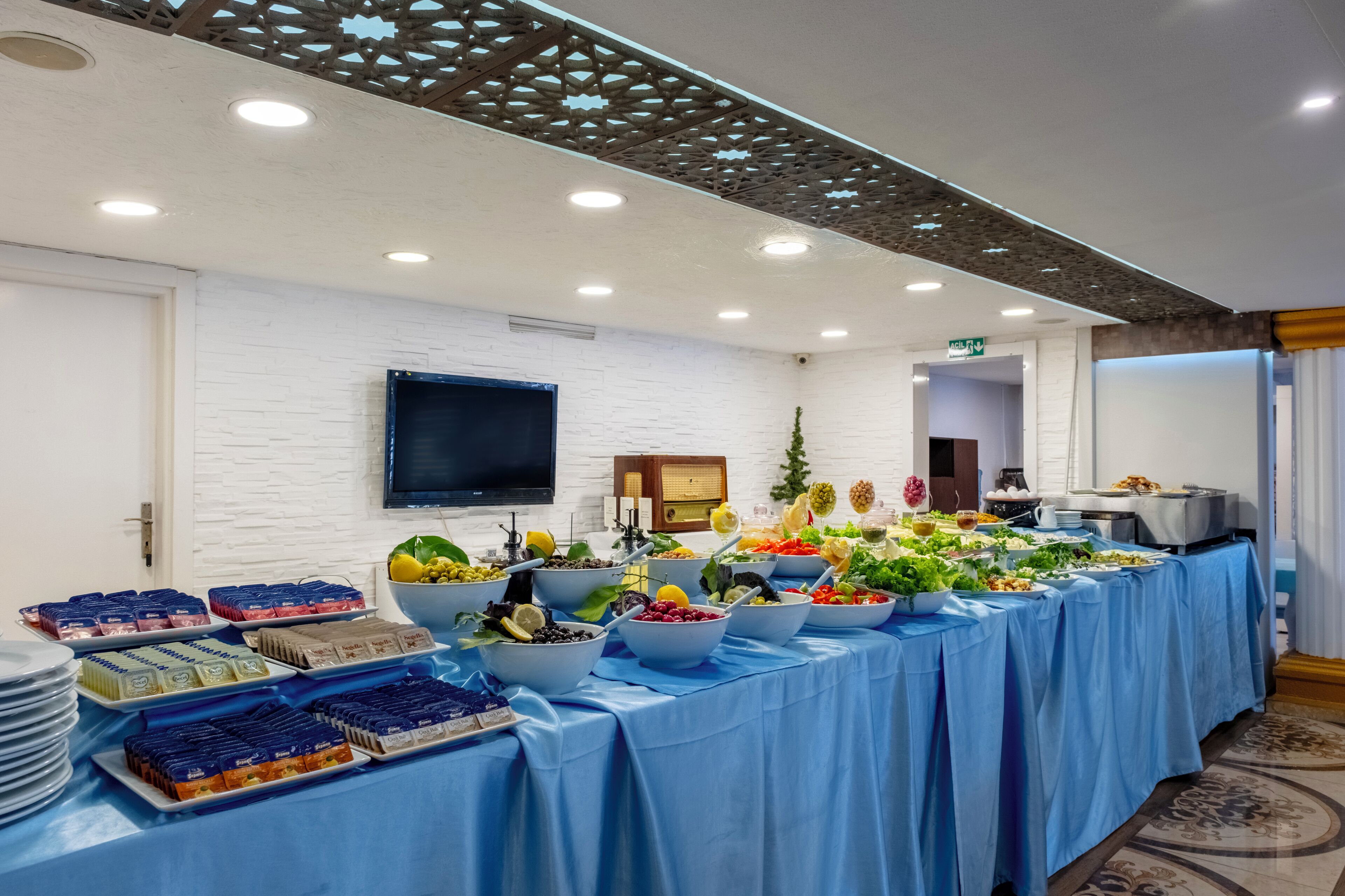 Une table de buffet garnie de divers plats et un téléviseur à écran plat fixé au mur.