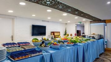 Une table de buffet garnie de divers plats et un téléviseur à écran plat fixé au mur.
