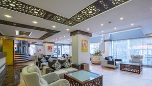 A spacious lobby with a modern design, featuring a seating area with sofas and armchairs, a coffee table, and a decorative ceiling. - Hotel Mevre (Antalya)