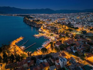 An aerial view of a coastal city with a marina, buildings, and a fortified area. - Hotel Mevre (Antalya)