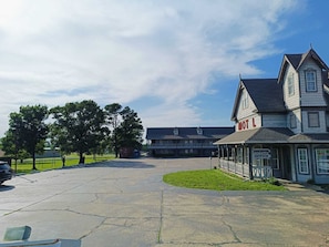 A motel with a large parking lot, a covered outdoor seating area, and a building with a 'MOTEL' sign. - Victorian Inn (Athens)