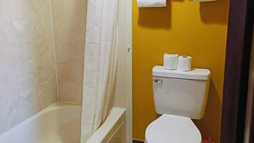 A bathroom with a bathtub, toilet, and shower curtain.