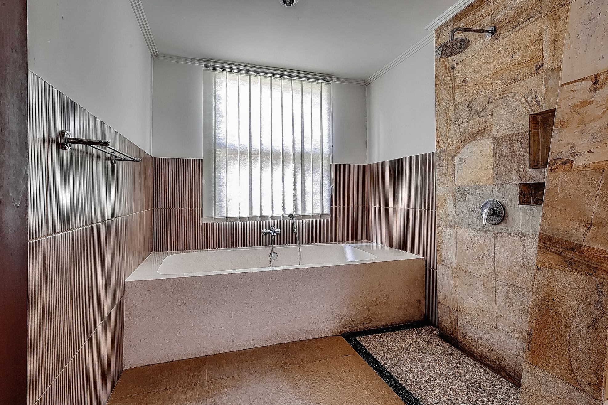 Ein modernes Badezimmer mit einer freistehenden Badewanne, einer Duschbrause und einem Fenster mit Jalousien.