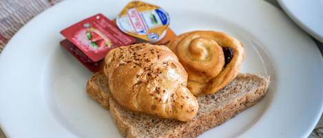 Un desayuno con un plato de croissant y mantequilla, un vaso de jugo de naranja y una taza de café sobre una mesa de mármol.