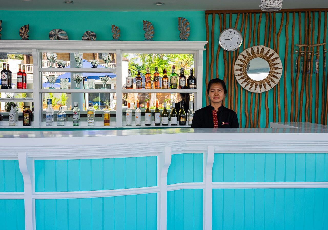 Zona de bar con diversas botellas y un reloj en la pared.