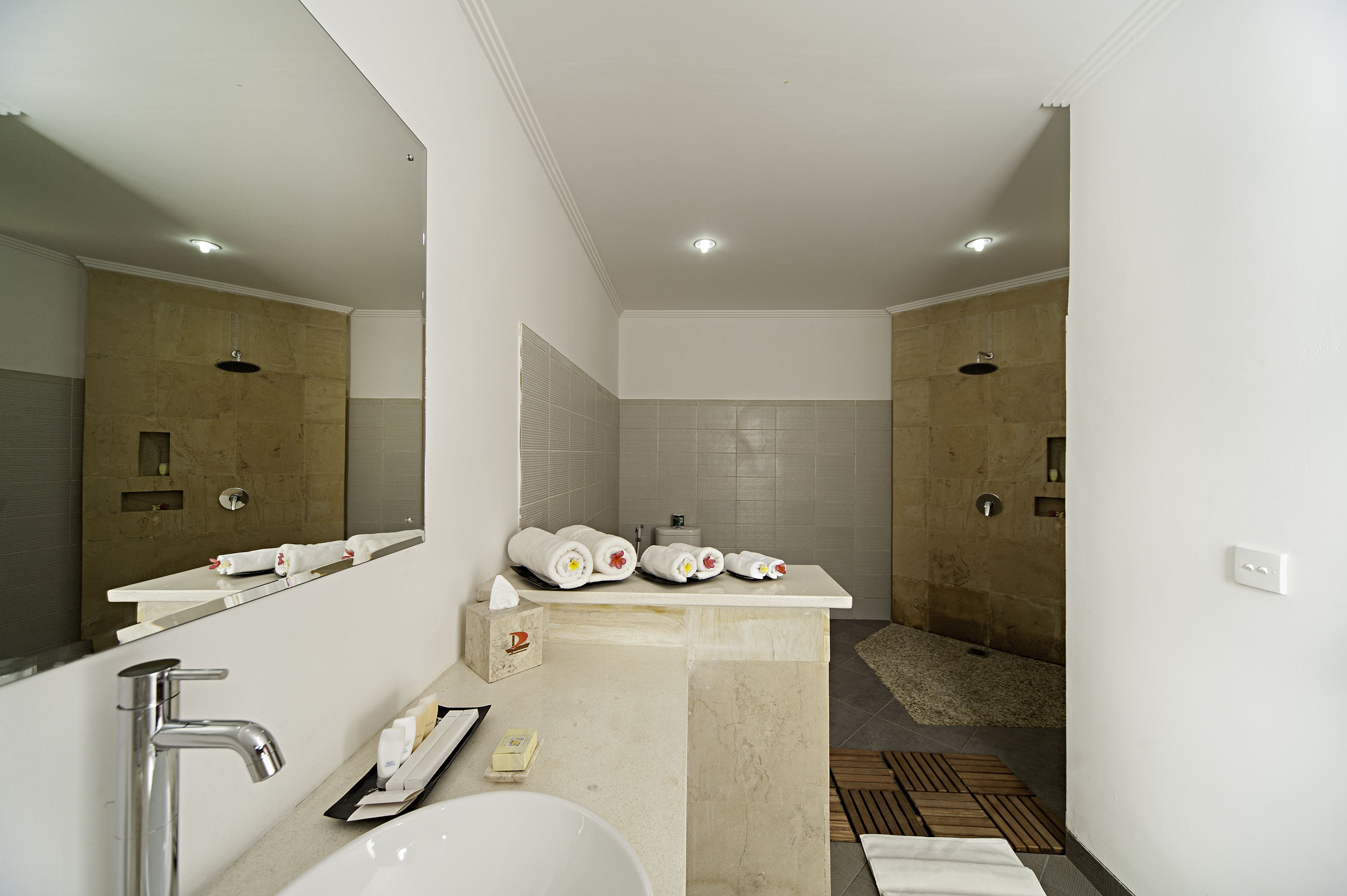 A modern bathroom with a large mirror, a sink, and a shower area.