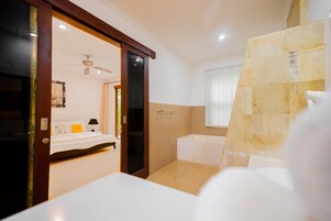 Una habitación de hotel con cama, baño con bañera y zona de ducha.