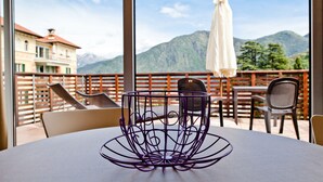 A balcony with a table and chairs, overlooking a mountainous landscape. - Residence Lenno (Tremezzina)