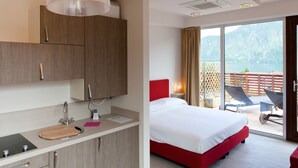 A hotel room with a modern design, including a large bed with red headboard, a separate bathroom with a sink and mirror, and a balcony with a view of the water. - Residence Lenno (Tremezzina)