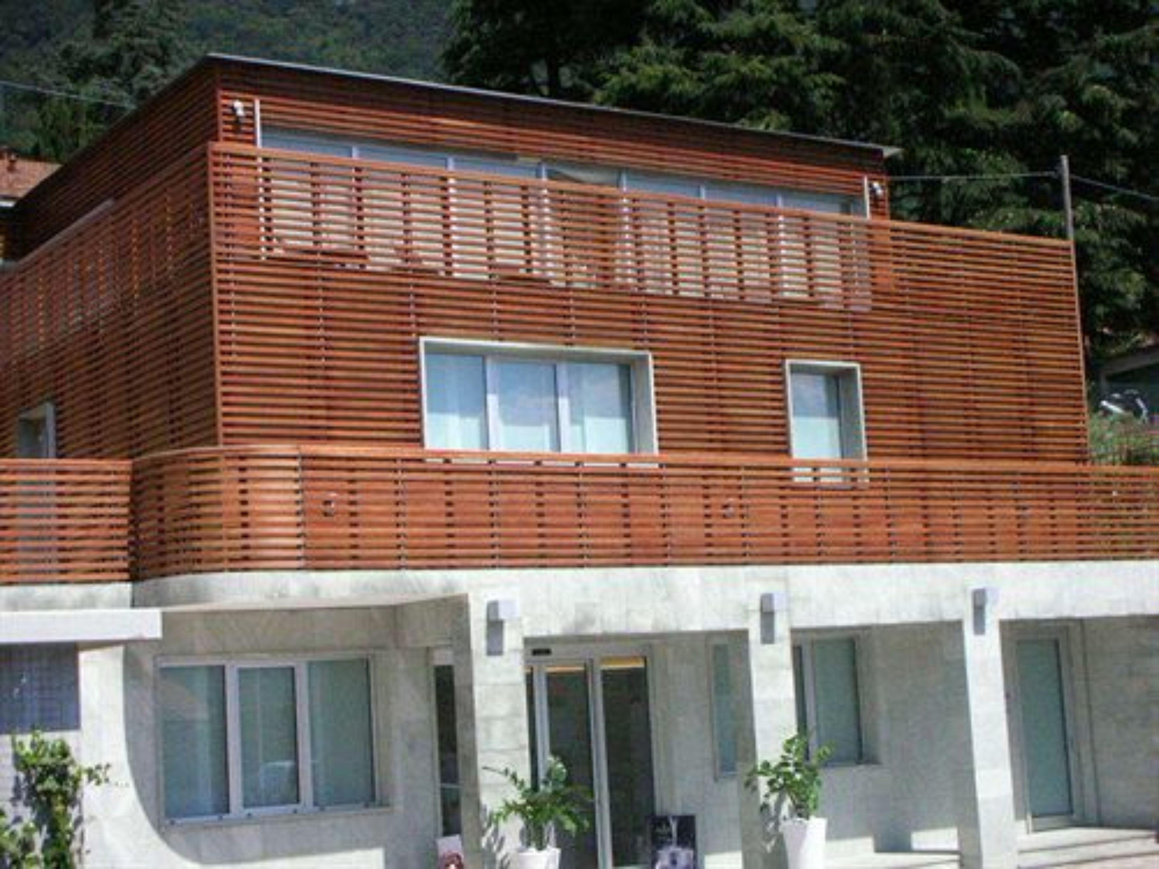 Een modern gebouw met twee verdiepingen, een houten gevel en grote ramen.