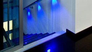 A stairwell with a glass door, blue lighting, and an emergency exit sign. - Residence Lenno (Tremezzina)