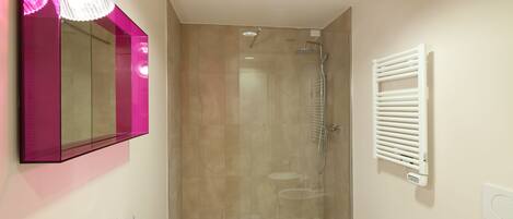 A modern bathroom with a glass shower enclosure, a white sink, and a mirror with a pink frame.