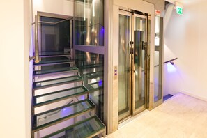 A modern elevator with glass doors and a metal handrail. - Residence Lenno (Tremezzina)