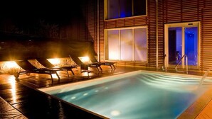 A swimming pool with lounge chairs and a building with large windows and a door. - Residence Lenno (Tremezzina)