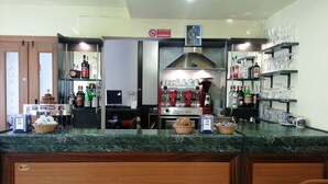 A bar area with a coffee machine, shelves with bottles, and a sign prohibiting smoking. - Hotel Clodia (Chioggia)