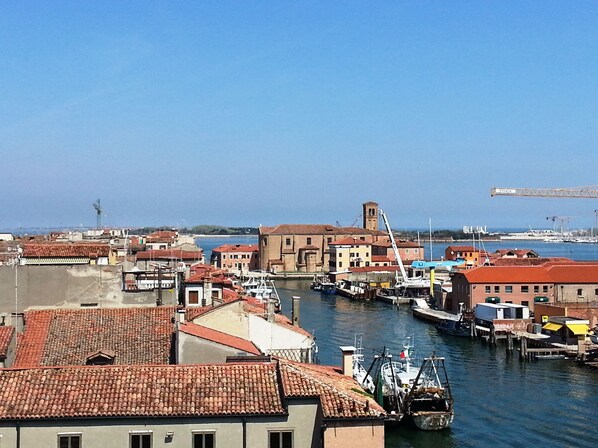 A coastal town with buildings along the waterfront, a marina with boats, and a crane in the background.