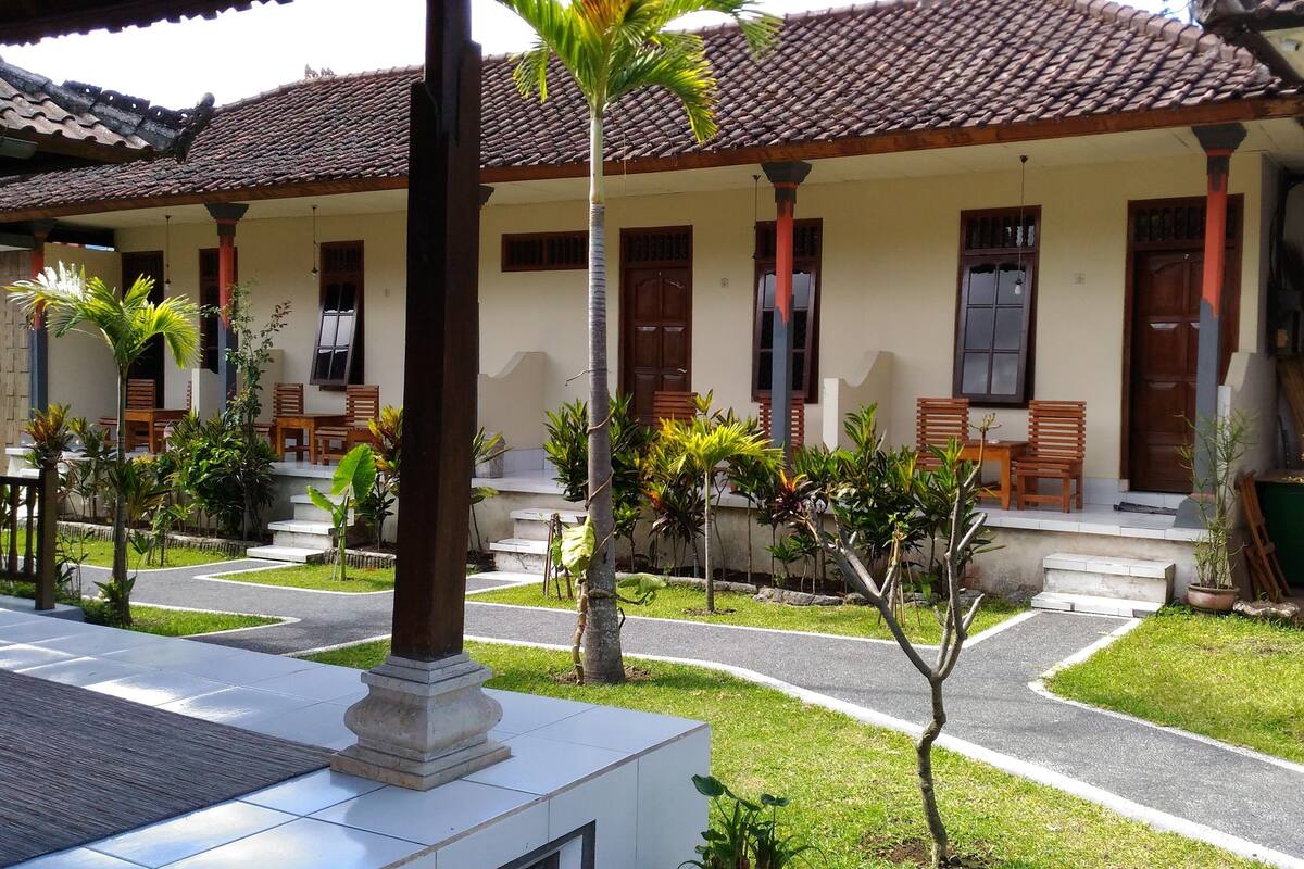 A traditional building with a tiled roof, wooden columns, and a covered porch with wooden chairs.