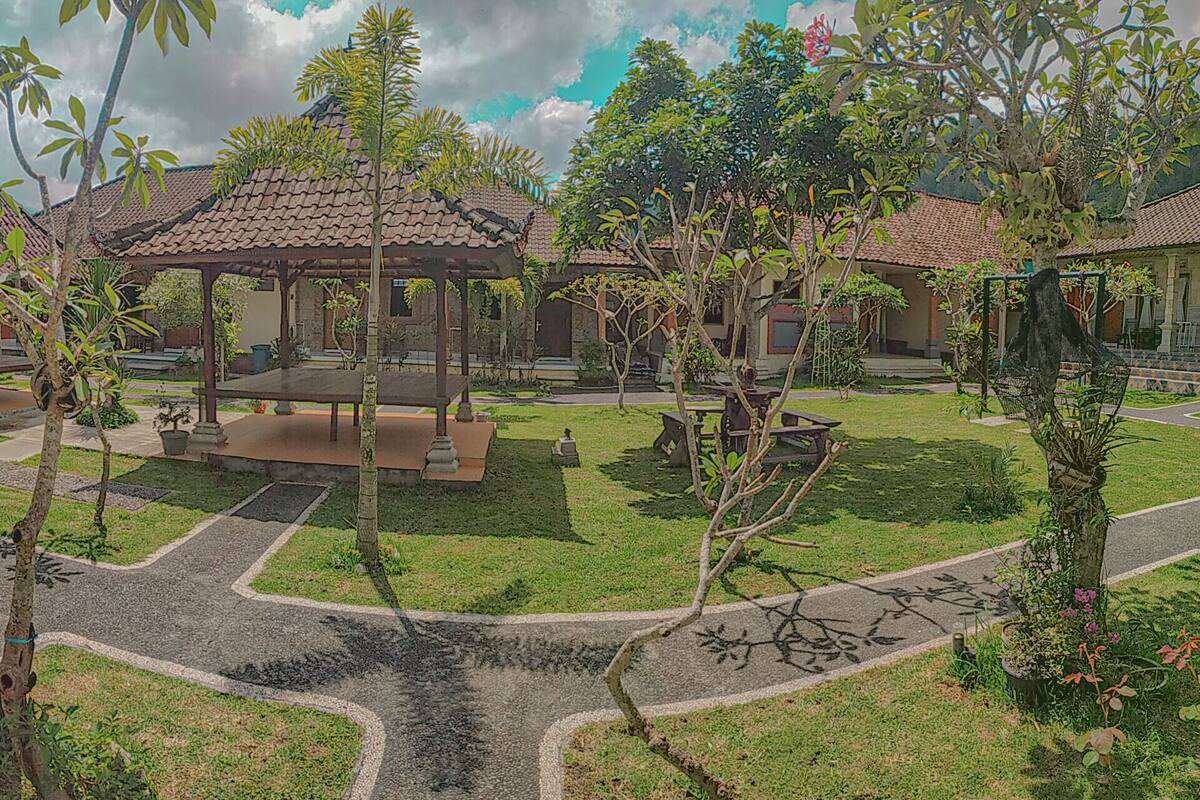 A courtyard with a gazebo, tiled pathways, and small trees.