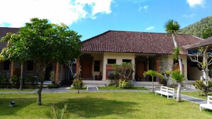 A traditional house with a tiled roof, a porch, and a well-maintained lawn. - Segara Hotel and Restaurant (Kintamani)