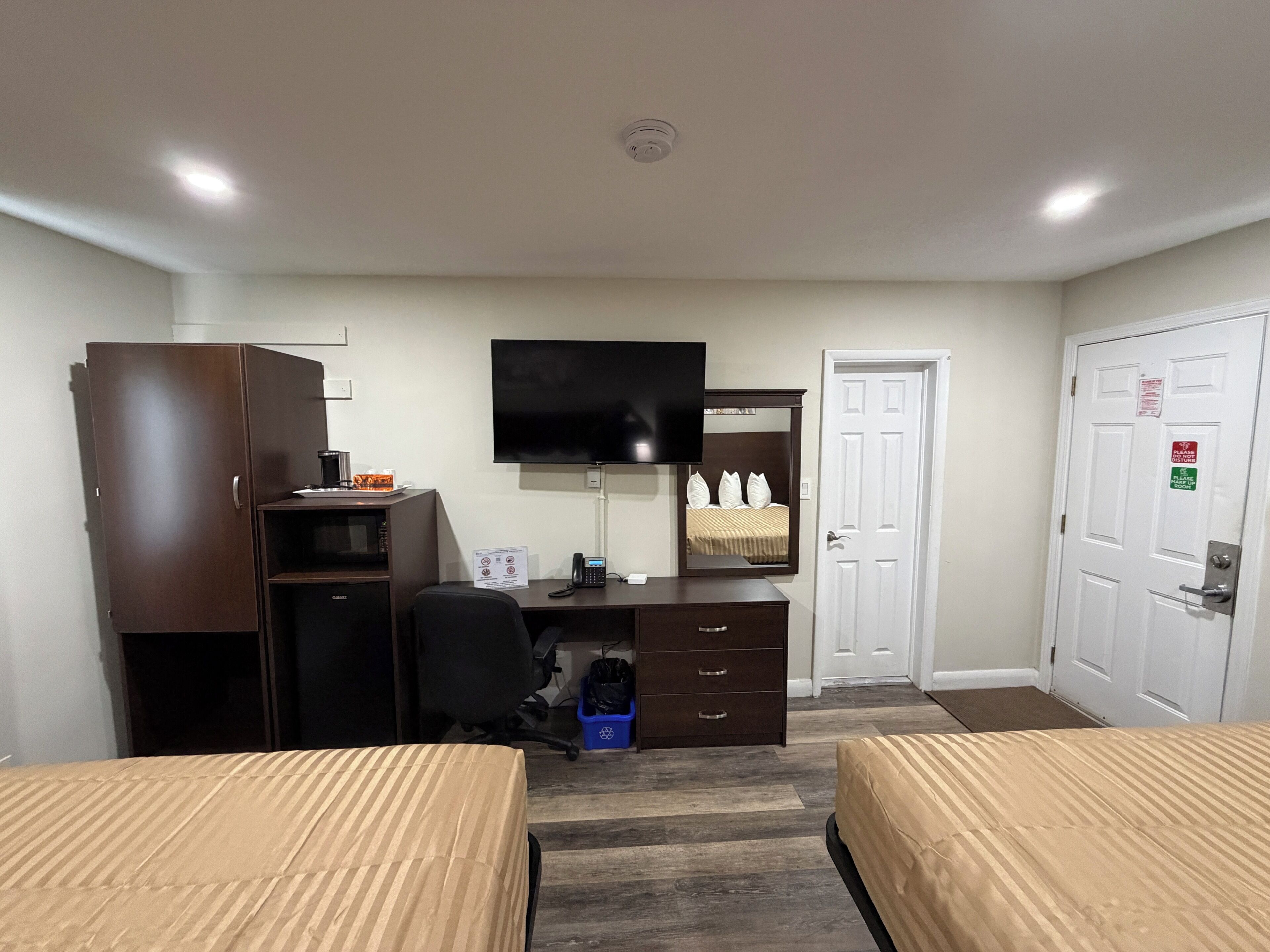 A hotel room with a bed, a desk, a chair, a television, a wardrobe, and a door.