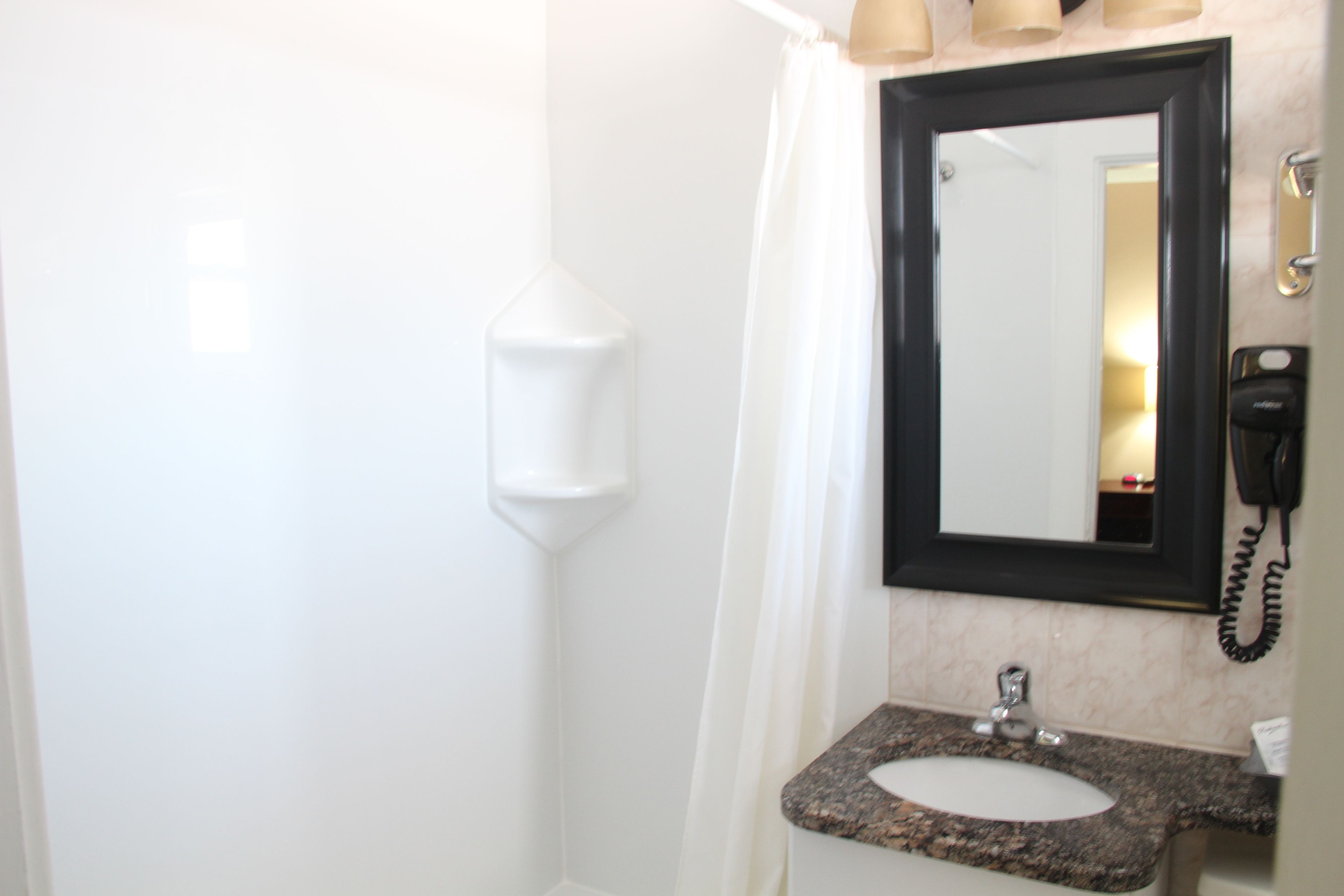 A bathroom with a white sink, a mirror, and a telephone.