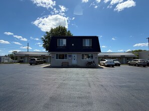 Un motel de dos pisos con estacionamiento, un banco y una motocicleta estacionada afuera.