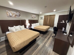 Habitación de hotel con dos camas, un escritorio, una silla, un televisor y obras de arte en las paredes.