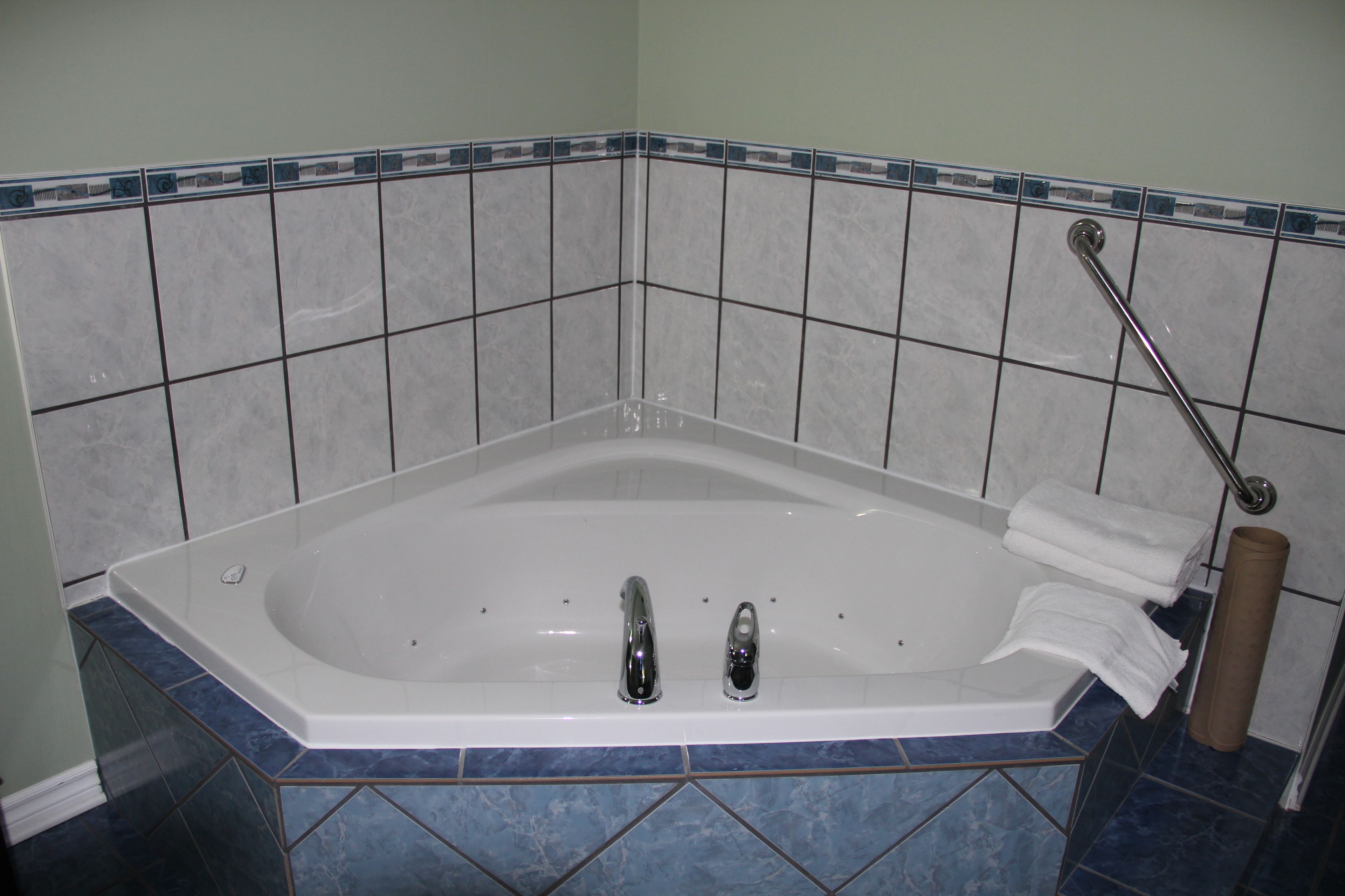 Ein Badezimmer mit einer Badewanne, zwei Wasserhähnen und einem Handtuchhalter.