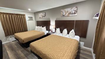 Una habitación de hotel con dos camas, un cabecero, un cuadro y una ventana con cortinas.