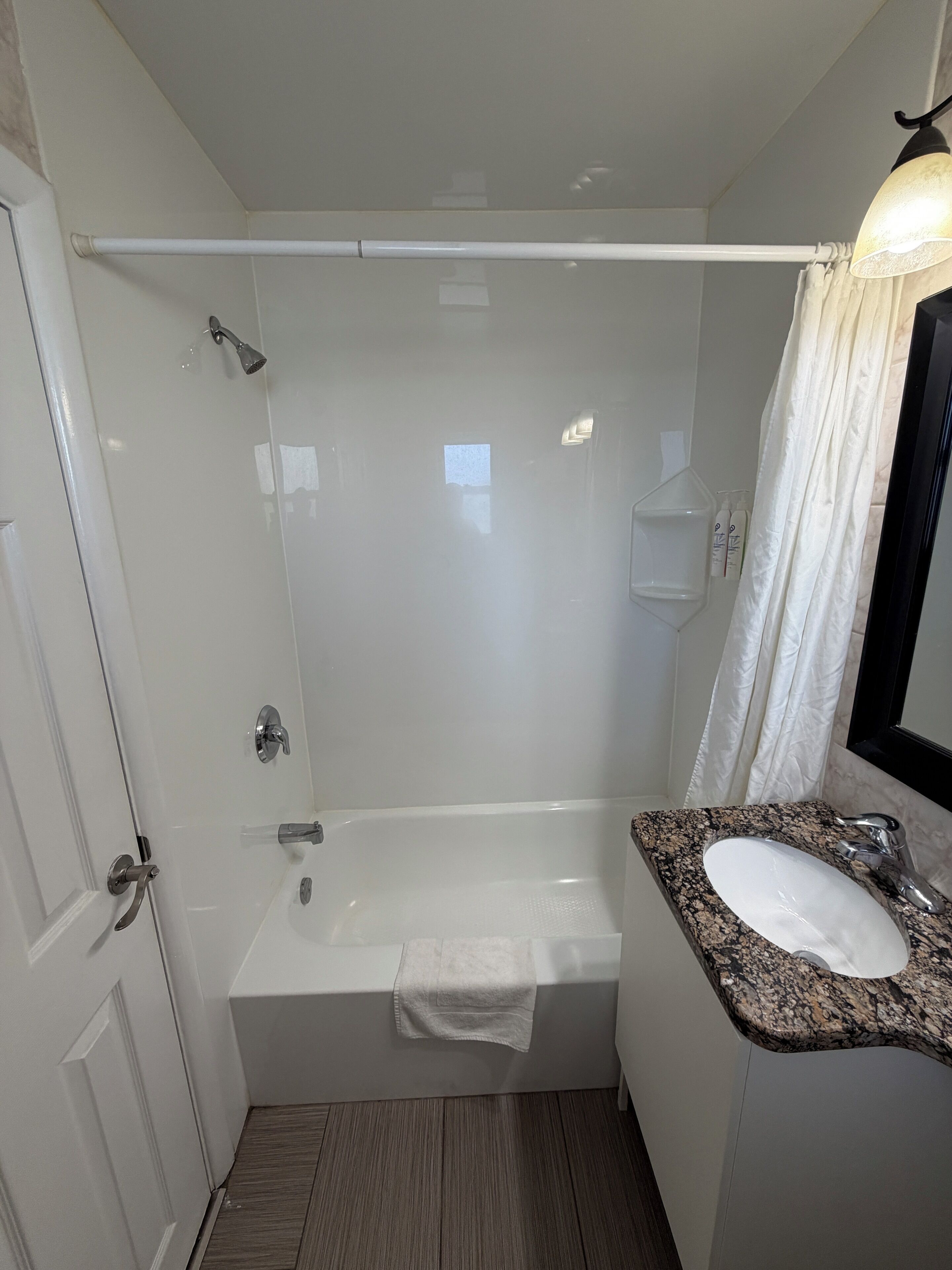 A bathroom with a bathtub, a sink, a shower, and a towel rack.