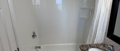 A bathroom with a bathtub, a sink, a shower, and a towel rack.