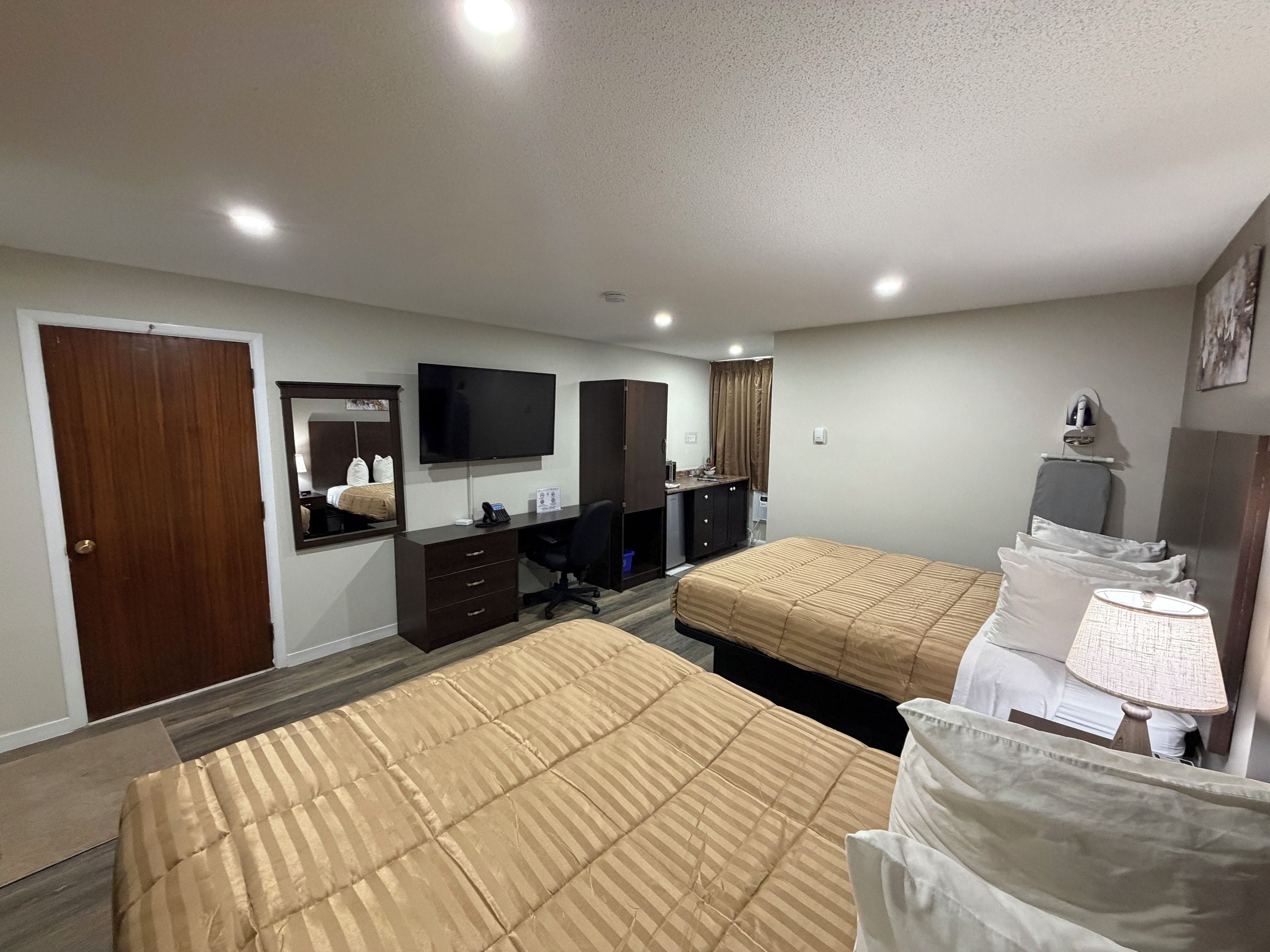 Quarto de hotel com duas camas, uma escrivaninha, televisão e espelho.