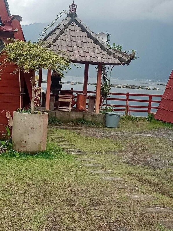 A gazebo with a tiled roof, surrounded by a wooden fence and potted plants.