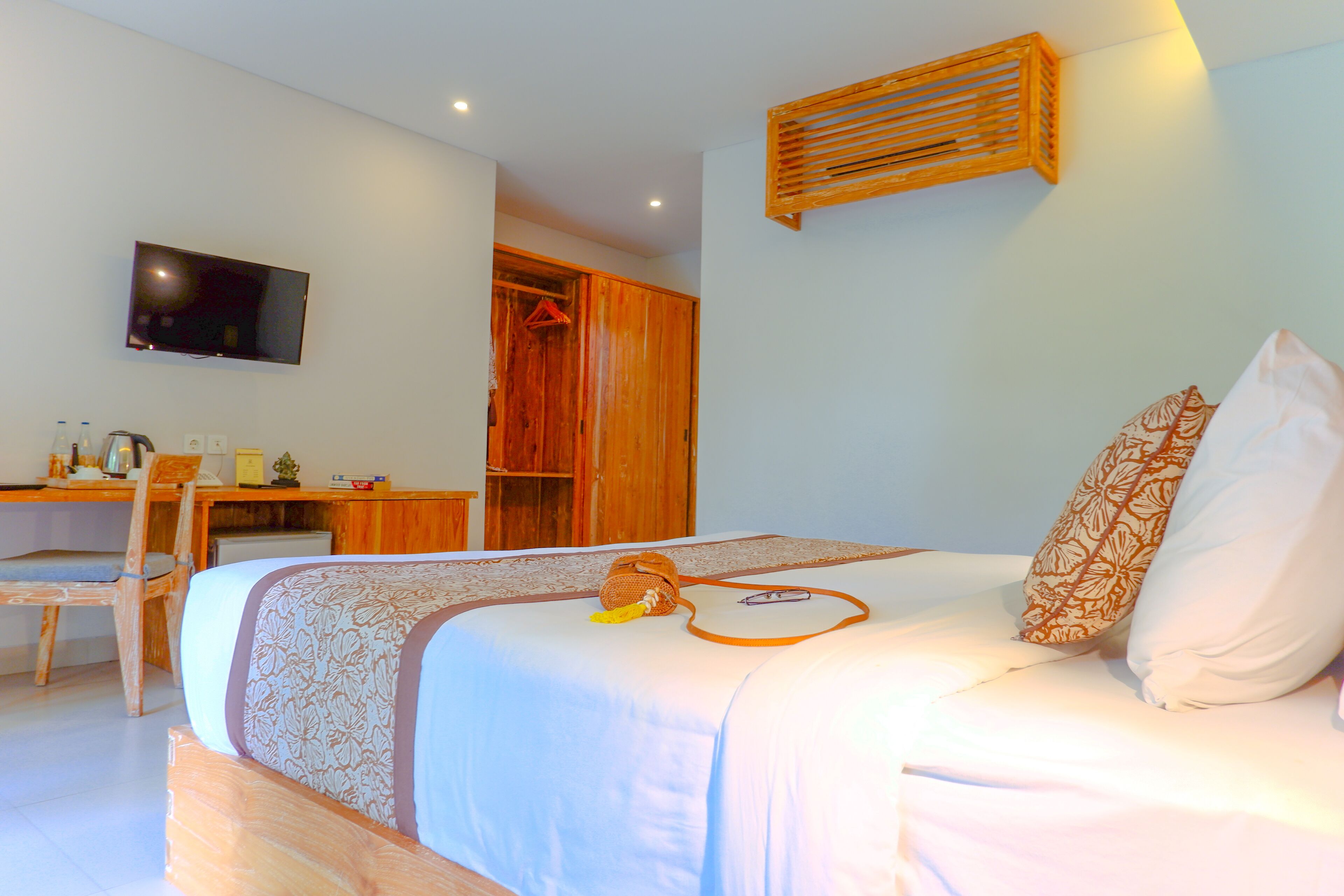 Een slaapkamer met een bed, een bureau, een stoel, een televisie en een kledingkast.