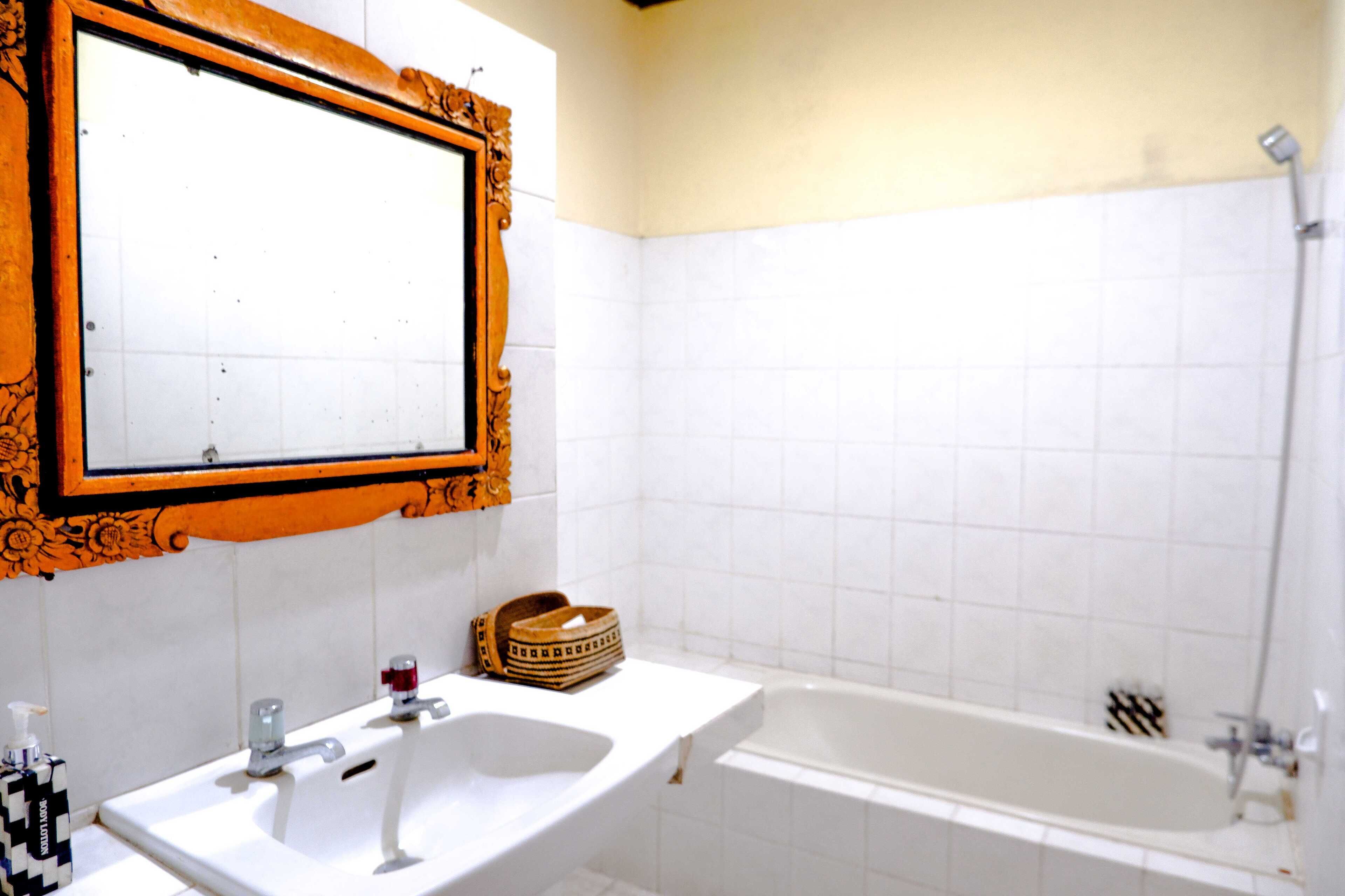 A bathroom with a large mirror, two sinks, a bathtub, and a shower.