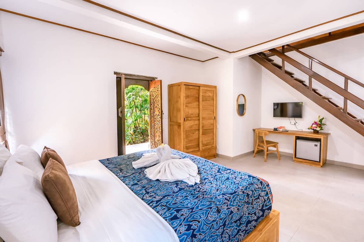 Quarto com cama, escrivaninha, televisão e escada.