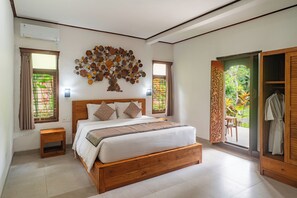 A bedroom with a wooden bed, a decorative tree wall art, a window with curtains, and a view of greenery outside. - Garden View Ubud (Ubud)