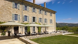 A stone building with outdoor seating and a view of the countryside.