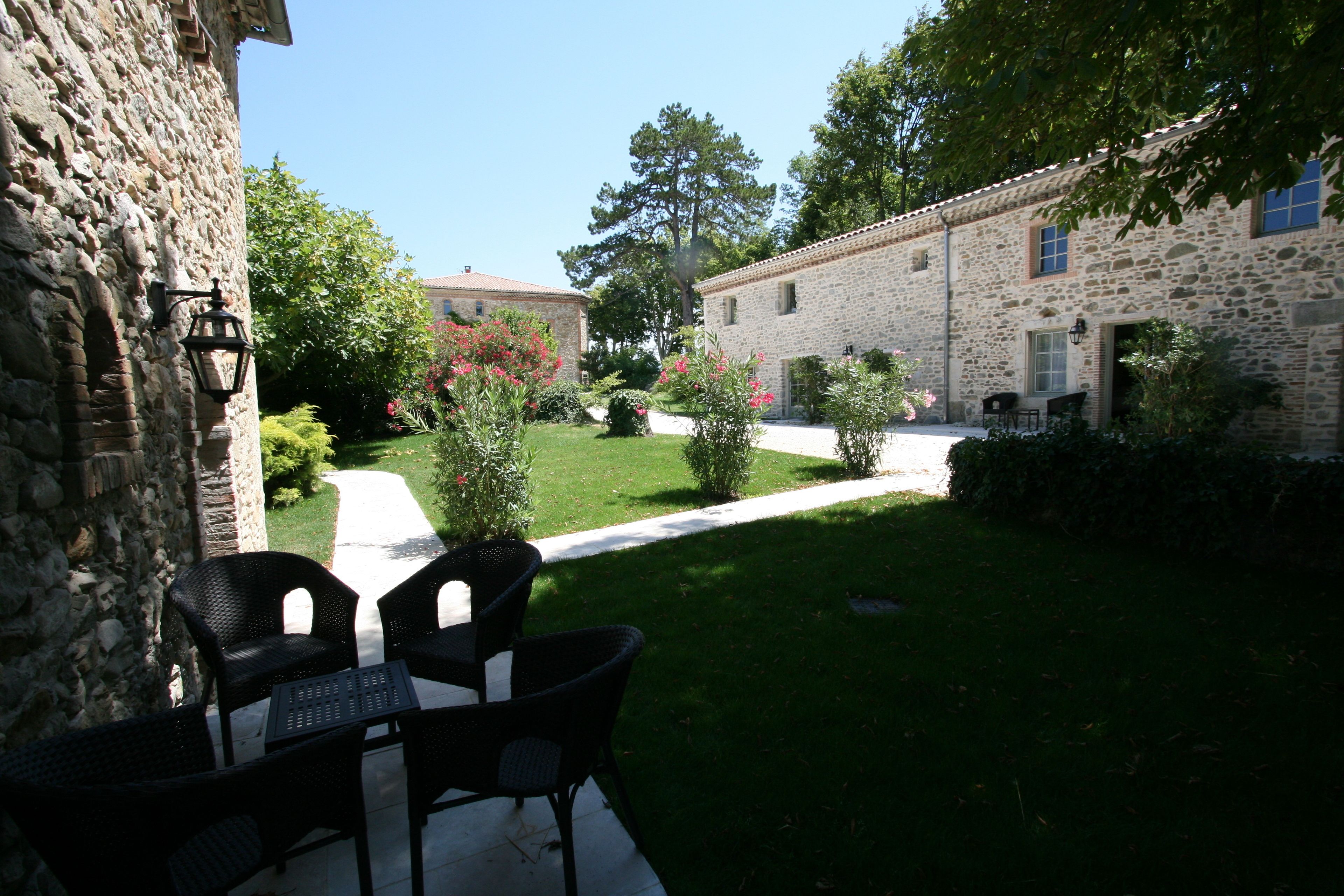 A stone building with a paved patio, outdoor seating, and a well-maintained garden.
