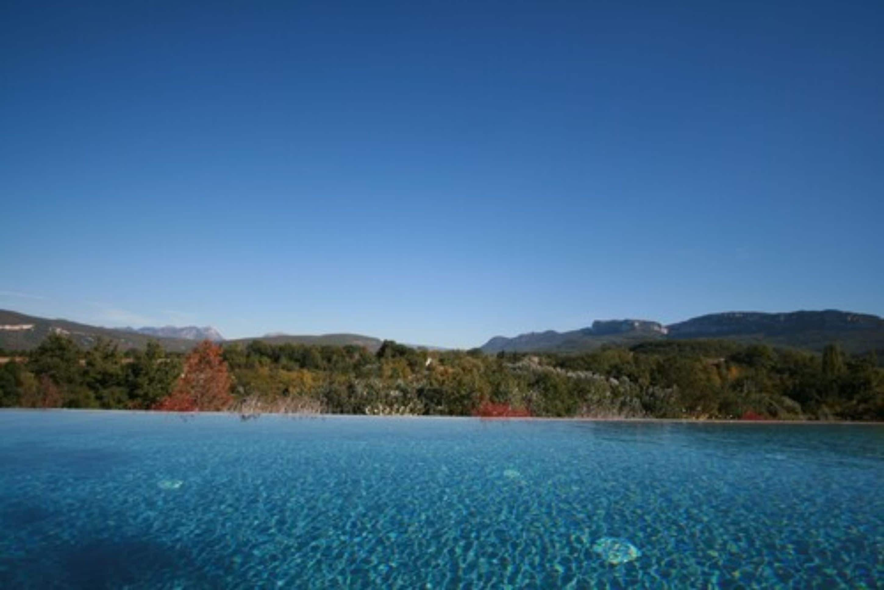 Una piscina azul cristalina con montañas al fondo.