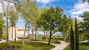 A castle-like building with a paved pathway leading to it, surrounded by trees and a well-maintained lawn.